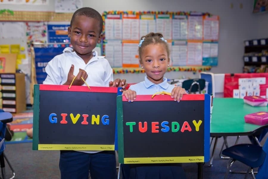 two kids holding giving Tuesday signs